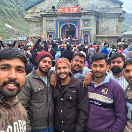 Group of pilgrims posing for a photo in front of the sacred Kedarnath Temple during the Kedarnath Yatra in Uttarakhand.