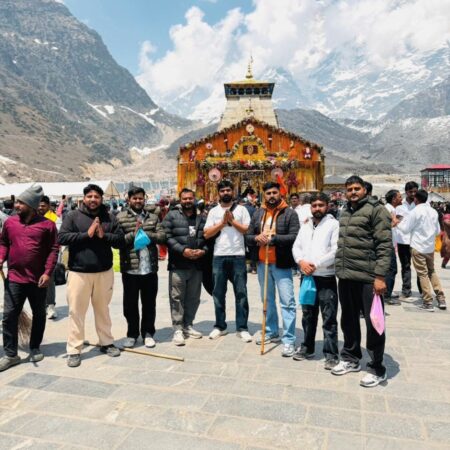 Group pilgrims standing in front of Kedarnath Temple during the Uttarakhand yatra