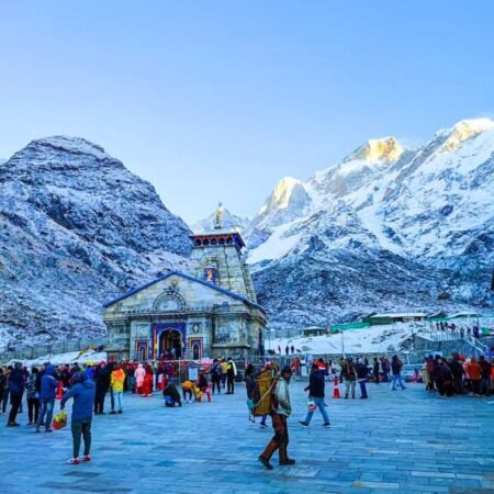 Pilgrims at Kedarnath Temple surrounded by snow-covered Himalayan mountains in Uttarakhand