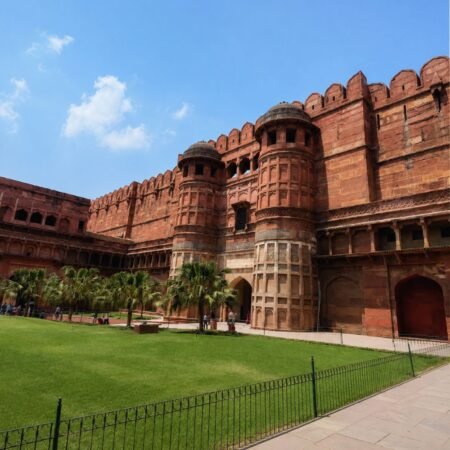 Wide-angle view of Agra Fort showcasing its massive red sandstone walls, historic Mughal architecture, landscaped gardens, and iconic bastions in Agra, Uttar Pradesh.