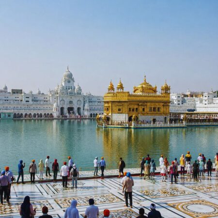 Full view of the Golden Temple (Sri Harmandir Sahib) in Amritsar with the Amrit Sarovar, marble parikrama, and devotees during the daytime.