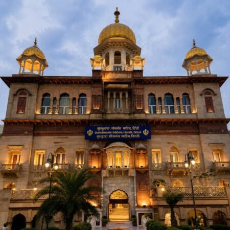 Front view of Gurdwara Sis Ganj Sahib in Anandpur Sahib, Punjab, showcasing its illuminated Sikh architecture, golden domes, grand entrance, and peaceful surroundings at dusk.