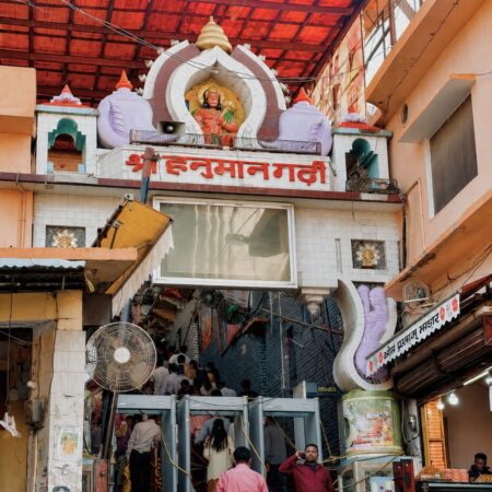 Main entrance of Hanuman Garhi Temple in Ayodhya featuring the iconic Hanuman shrine above the gateway, temple entrance staircase, and devotees entering the sacred temple complex.