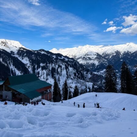 Snow-covered landscape at Solang Valley in Manali, Himachal Pradesh, featuring majestic Himalayan mountains, pine forests, and visitors enjoying the winter scenery.