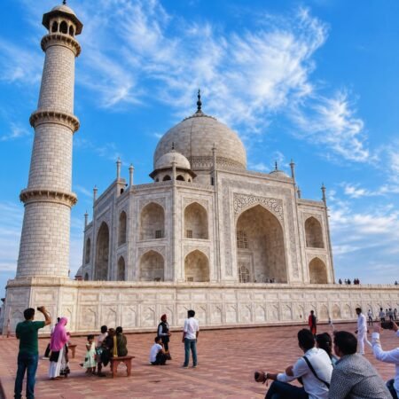 Side view of the Taj Mahal showcasing its white marble architecture and iconic minaret under a clear blue sky in Agra.