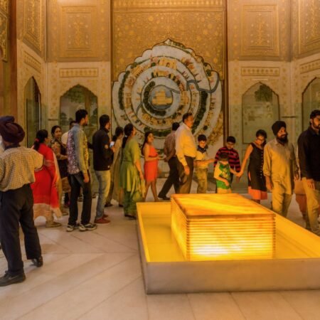 Visitors exploring an exhibition gallery inside the Virasat-e-Khalsa Museum in Anandpur Sahib, featuring Sikh heritage artwork, illuminated displays, and ornate interior architecture.