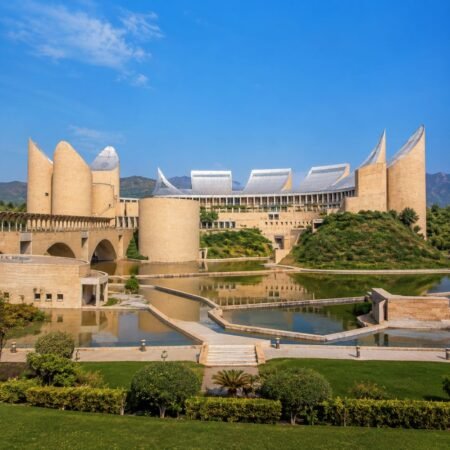 Front panoramic view of Virasat-e-Khalsa Museum in Anandpur Sahib, Punjab, featuring its iconic modern architecture, reflecting pools, landscaped gardens, and surrounding Shivalik Hills under a clear blue sky.