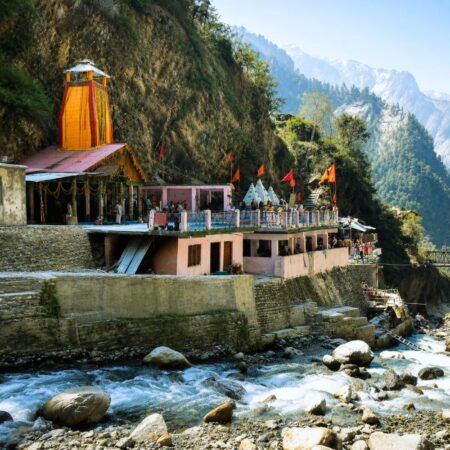 Riverside view of Yamunotri Temple surrounded by Himalayan mountains and flowing river in Uttarakhand.