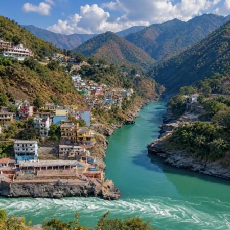 Aerial view of Devprayag Sangam with turquoise rivers, Himalayan mountains and hillside town in Uttarakhand
