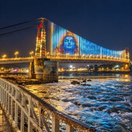 Illuminated suspension bridge over the Ganga River in Rishikesh at night with colorful lights and river reflections