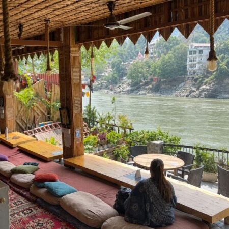 Riverside cafe in Rishikesh overlooking the Ganga River with a peaceful mountain and hillside view